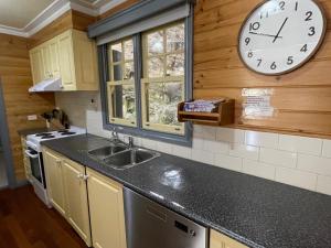 a kitchen with a clock on the wall and a sink at Sails - elegant, spacious beach villa in Port Fairy