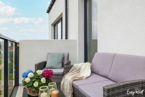 a patio with a couch and flowers on a balcony at Dwupoziomowy apartament Grande in Rewal
