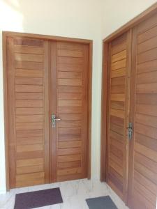 two wooden doors in a room with mats at INJIHAR HOUSE in Ubud