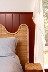 a bed with a rattan headboard next to a window at Log Box Red Hill in Red Hill South
