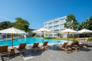 Royal Yao Yai Island Beach Resort في كو ياو ياي: فندق فيه كراسي ومظلات بجانب مسبح