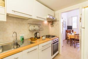 uma cozinha com armários brancos, um lavatório e uma mesa em Libeccio House - Happy Rentals em Avola
