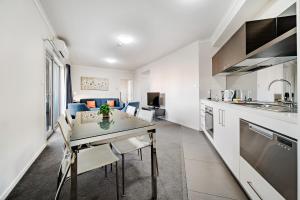 a kitchen and living room with a table and chairs at Comfy Lakeside 1-Bed with Secure Parking in Tuggeranong