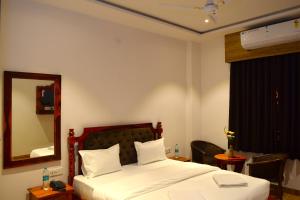 1 dormitorio con 1 cama con espejo y silla en Hotel Mewar Mahal, en Udaipur
