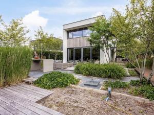 ein modernes Haus mit Glasfenstern und einem Garten in der Unterkunft Wellness villa on the water near Harderwijk in Zeewolde