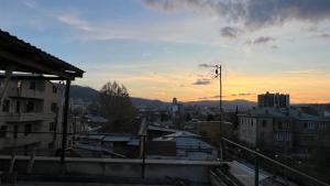 - une vue sur une ville avec le coucher du soleil en arrière-plan dans l'établissement Garden House Tbilisi, à Tbilissi