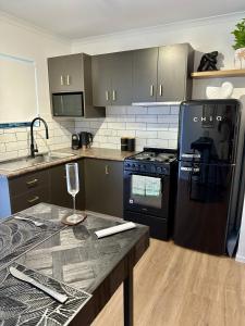 a kitchen with black appliances and a table with a wine glass at Luxe Palm Studio Villa - In the heart of Edge Hill in Edge Hill