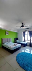 a bedroom with two beds and a green wall at De Viana Apartments Homestay in Kota Bharu
