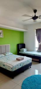 twee bedden in een kamer met een groene muur bij De Viana Apartments Homestay in Kota Bharu