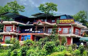 a red building with a sign in front of it at GAUTAM GARDEN GUEST HOUSE in Pokhara