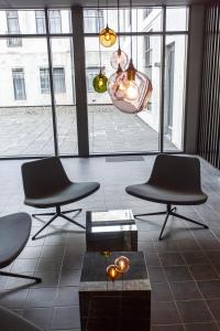 a living room with two chairs and a table and windows at Skuggi Hotel by Keahotels in Reykjavík