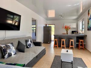uma sala de estar com um sofá e uma cozinha em Maison Te Manu - plage privée avec vue sur Tahiti à quelques pas em Maatea