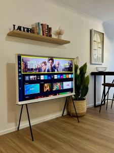TV grande en un stand en la sala de estar en Luxe Palm Studio Villa - In the heart of Edge Hill en Edge Hill