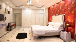 une chambre avec un lit blanc et un mur rouge dans l'établissement Close, à Islamabad