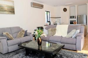 a living room with two couches and a coffee table at Bj comfy home in Wellard