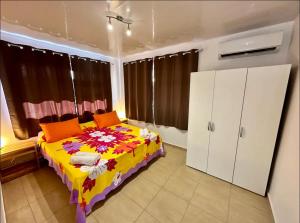um quarto com uma cama com um cobertor colorido em Maison Te Manu - plage privée avec vue sur Tahiti à quelques pas em Maatea