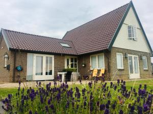 a house with a pitched roof and purple flowers at Landhuis Mariëtta in De Koog