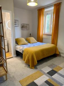 ein Schlafzimmer mit einem Bett mit einer gelben Decke darauf in der Unterkunft Les Sous Bois in Saint-Laurent-de-Brévedent