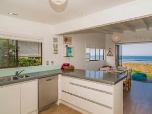 a kitchen with white cabinets and a large window at Beachfront Beauty - Whangamata Beachfront Home in Whangamata