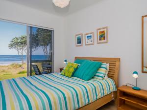 a bedroom with a bed with a view of the ocean at Beachfront Beauty - Whangamata Beachfront Home in Whangamata