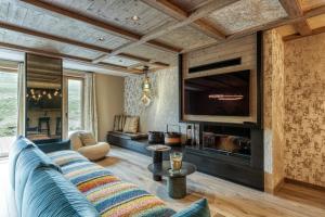a living room with a couch and a tv at Eskape Megève - K3 and Eskape Megève - S2- Happy Rentals in Megève