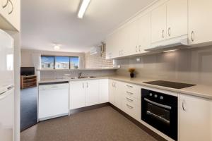 a kitchen with white cabinets and a stove top oven at Marine Cove Resort in Goolwa South