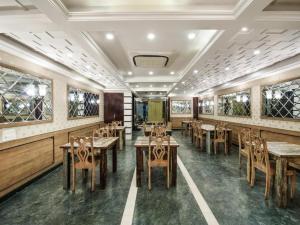 a restaurant with wooden tables and chairs and windows at Umed in Jodhpur