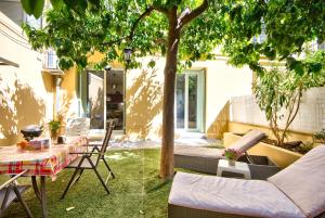 a patio with a table and chairs under a tree at la palais osiris Nice centre jardin wifi clim parking in Nice