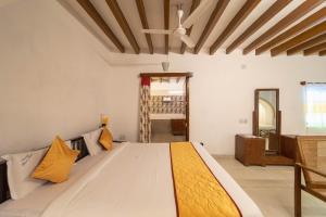 a bedroom with a large bed with yellow pillows at Dumas Guest House in Puducherry