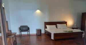 1 dormitorio con 1 cama y 1 silla en Bluewind Resort, en Tangalle