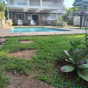a yard with a swimming pool in front of a house at Wylie Hall Guesthouse in Durban