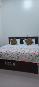 Murli Manohar Palace في فريندافان: سرير عليه غطاء من الزهور ومخدات