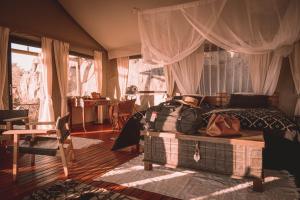 a bedroom with a bed and a large window at Ohorongo Tented Camp in Kaneb Pos