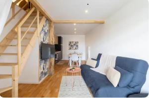 ein Wohnzimmer mit einem blauen Sofa und einer Treppe in der Unterkunft Charmant T4 in Briord