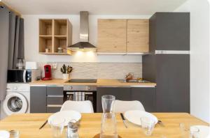 eine Küche mit einem Holztisch mit Stühlen und eine Küche mit einer Spüle in der Unterkunft Charmant T4 in Briord