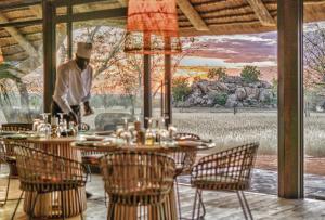 a man standing in front of a table with chairs at Ohorongo Tented Camp in Kaneb Pos