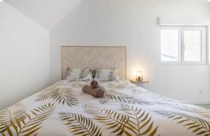 ein Schlafzimmer mit einem großen Bett mit einer großen, mit Laubdruck bedruckten Tagesdecke in der Unterkunft Charmant T4 in Briord