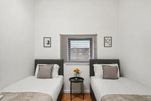 twee bedden in een kamer met witte muren en een raam bij Livestay - Two Bed London Apt with Balcony in Colindale