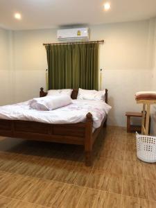 a bedroom with a bed with a green curtain at Thanid House in Ban Nai Khlong