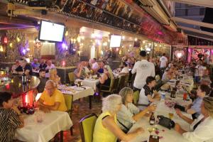 a group of people sitting at tables in a restaurant at HOTEL MİTOS in Alanya