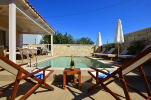 a swimming pool with two chairs and a bottle of wine at Villa Ithaca in Varípetron