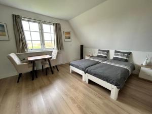 a bedroom with a bed and a desk and a window at Landhuis Mariëtta in De Koog