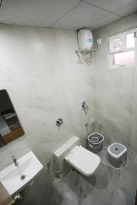 a white bathroom with a toilet and a sink at Maruti Grand Hotel in Rajkot