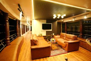 uma sala de estar com sofás de couro e uma televisão em IndraprasthamLakeCruise em Alappuzha