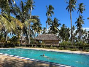 a person swimming in a pool with palm trees at Barry's Beach Resort in Mkwaja
