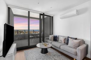 een woonkamer met een bank en een groot raam bij NEW Waterfront Living With Sublime Views 2B1B in Melbourne