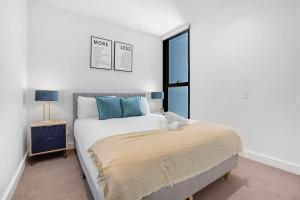 een witte slaapkamer met een bed en een raam bij NEW Waterfront Living With Sublime Views 2B1B in Melbourne