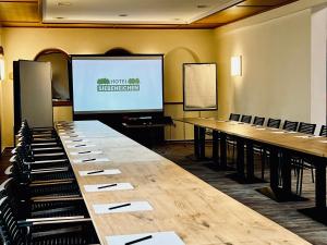 une salle de conférence avec une longue table devant un écran dans l'établissement Hotel Siebeneichen, à Meissen