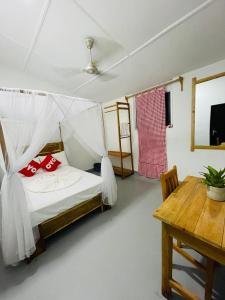 a bedroom with a bed with red pillows and a table at Swiss kiss beach resort in Uppuveli