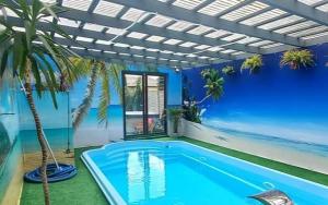 een zwembad met een blauwe muur en een palmboom bij APARTAMENT SOLNY in Rzeszów
